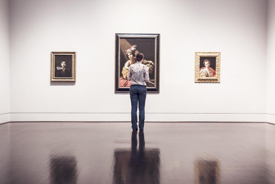 Salle de musée aux murs blancs avec tableaux exposés